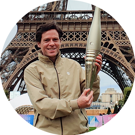 Close up of Ben holding the Olympic torch in front of the Eiffel Tower.