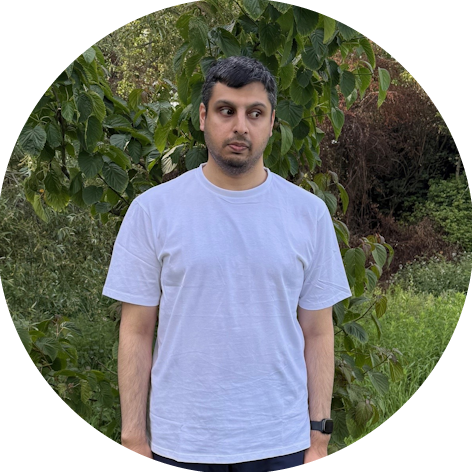 Close up of Saleem in a park with green and brown trees in the background